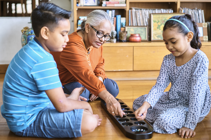 multigenerational family playing mancala game sitting on floor