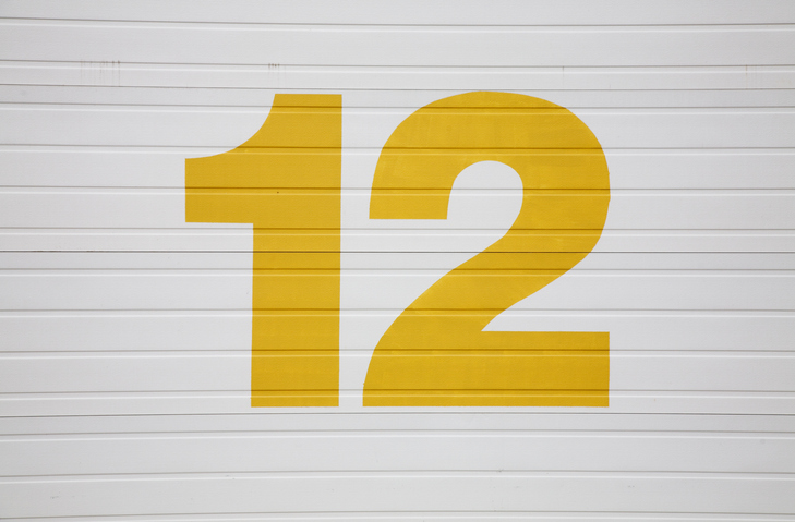 yellow number 12 painted on white garage door