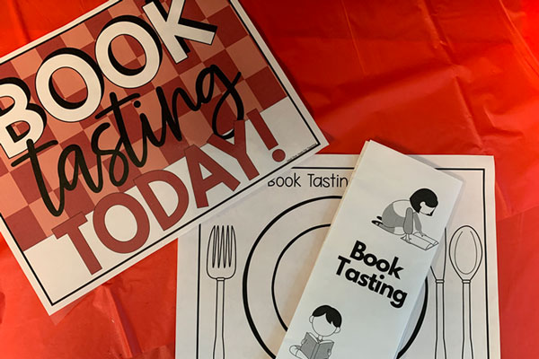 paper menu and sign on table with book tasting printed on them