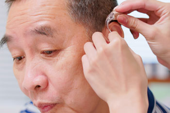 Older adult being fitted for a hearing aid.