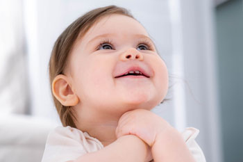 showing the head and shoulders of a baby smiling and looking up