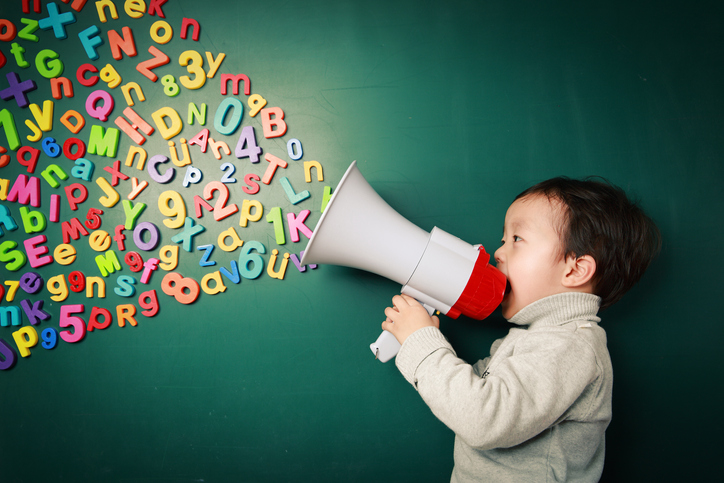 child holding megaphone with colorful letters coming out against green background