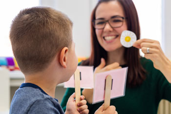 A preschooler practices correct pronunciation with a speech-language pathology assistant.