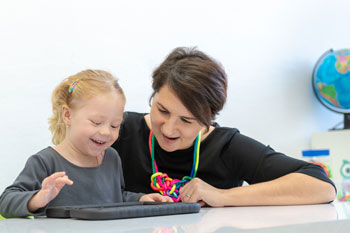 A young girl uses a tablet to communicate with her teacher.