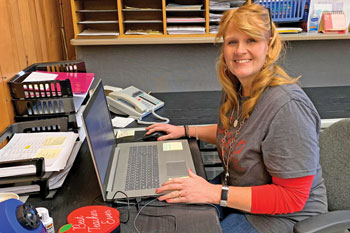 Christine Volz in her preschool office,seated at a desk in front of an open computer.