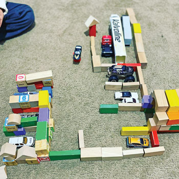 Toy cars backing in and out of their garage parking spots made of building blocks.