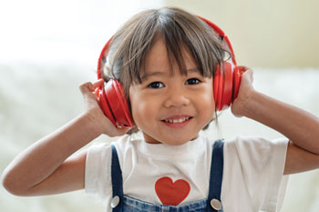 Photo of smiling young girl wearing bright red headphones.