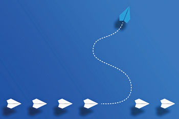 blue background with a row of white paper airplanes with one blue airplane going in a different direction